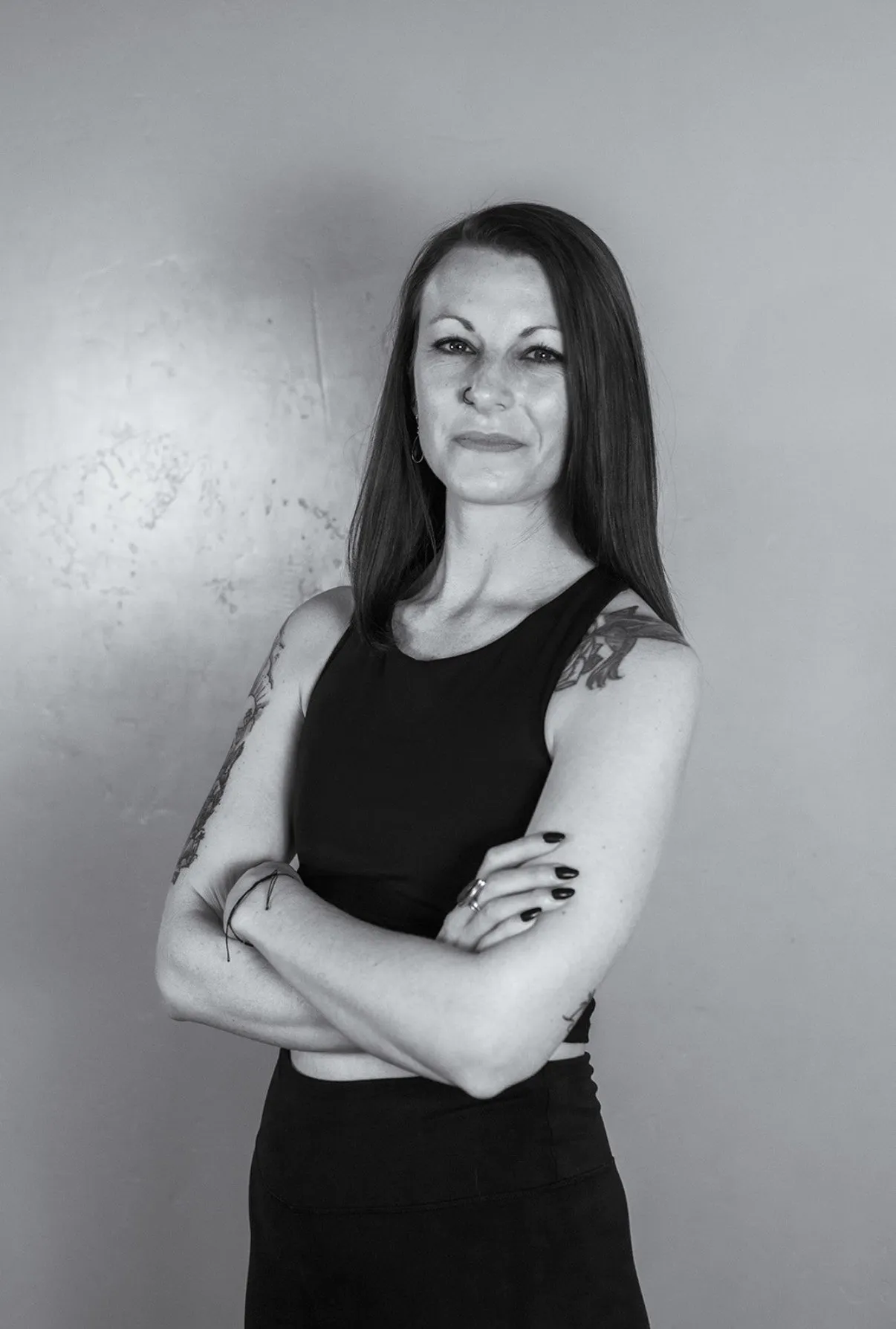 Black and white portrait of Cora Jewell, arms crossed, looking at the camera