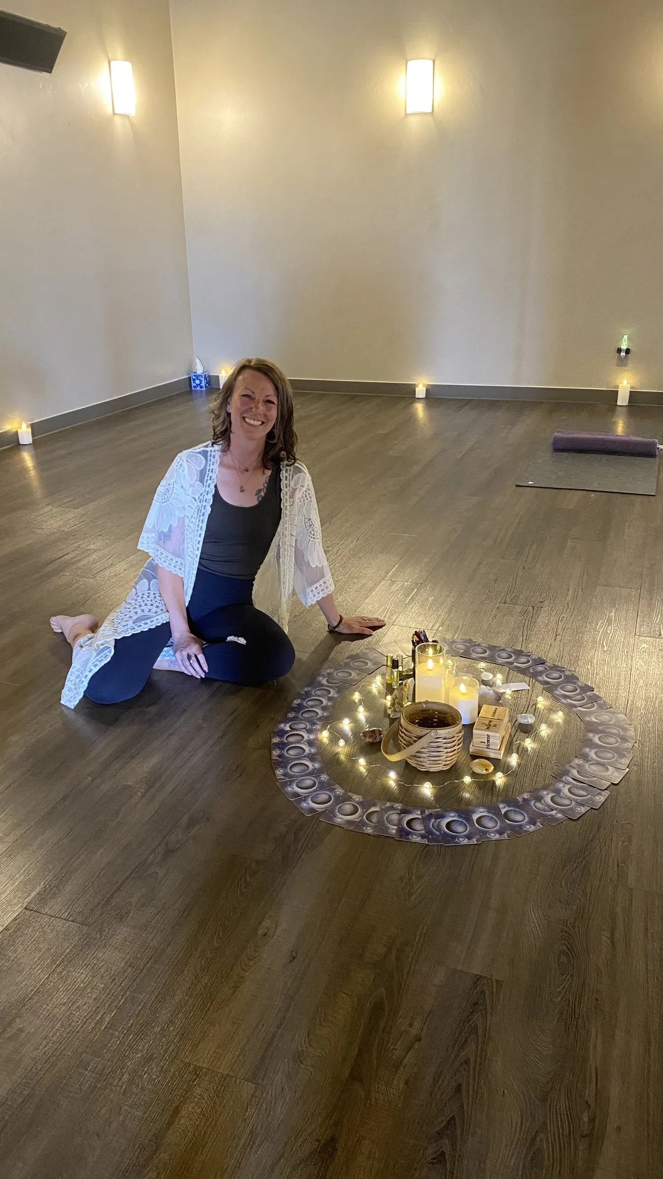 Cora seated beside a candlelit centerpiece circle in the yoga studio