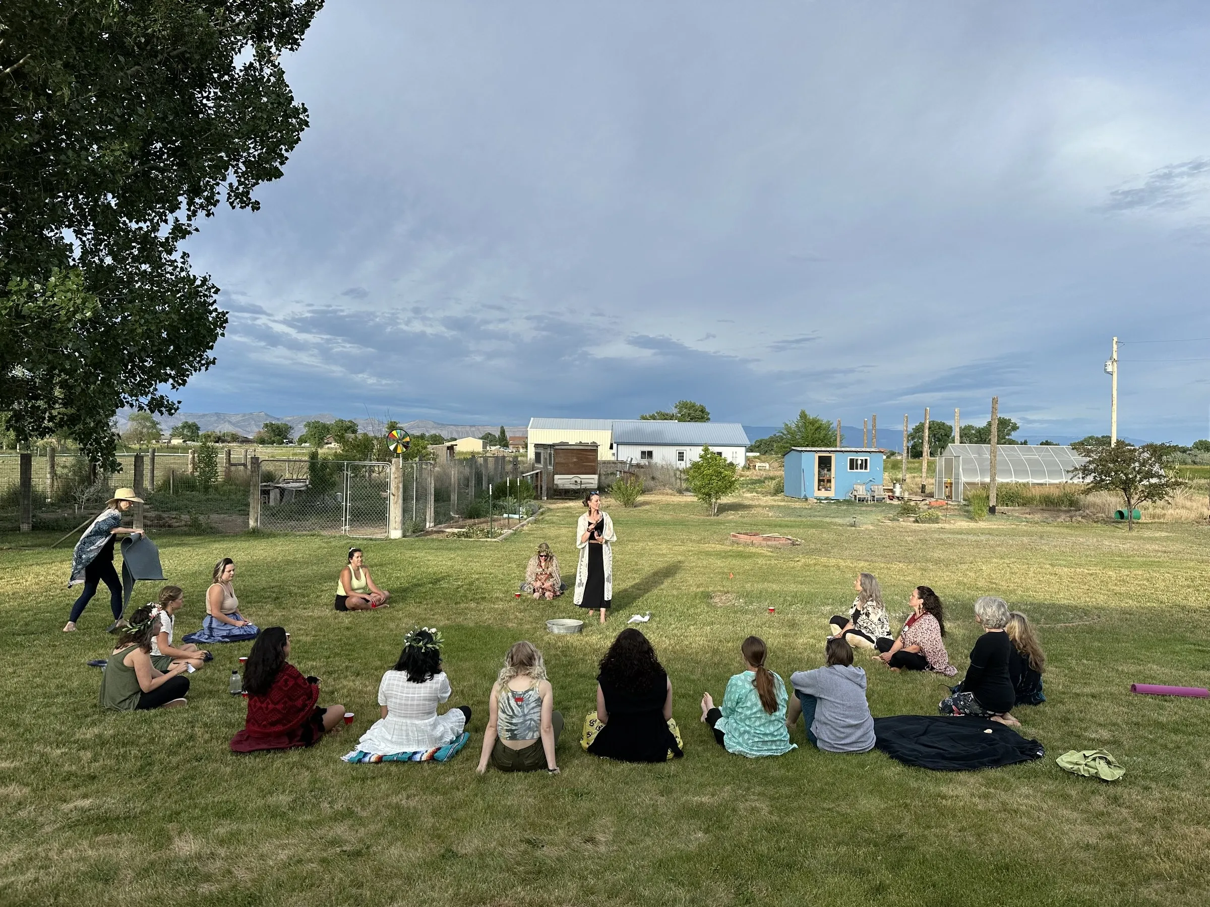 A circle of people gathered on the grass for an outdoor Soul Circle