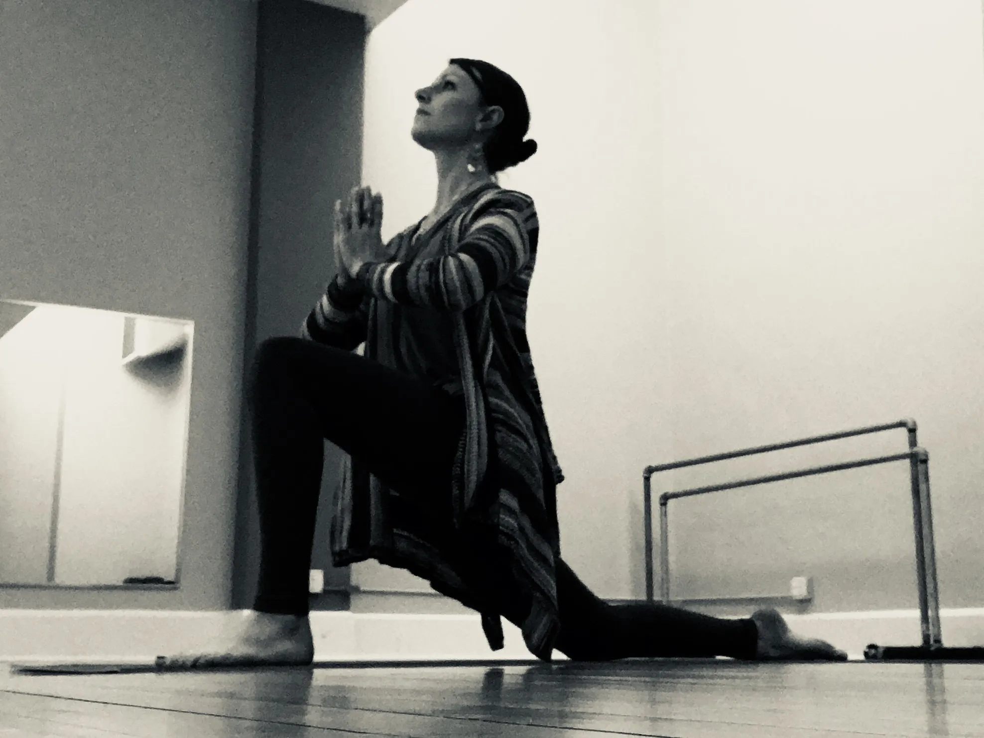 Cora in a low lunge with hands at heart center in the studio