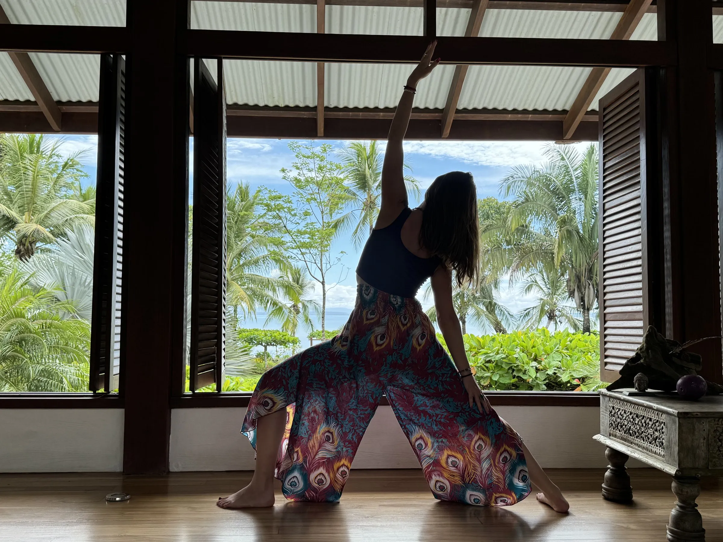 Cora practicing yoga in an open-air pavilion on a tropical retreat